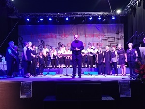 Ramón Lorente, director de la Coral, y los cantores de la Coral saludando al público