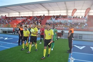 Los jugadores de los dos equipos junto a los árbitros saltando al campo