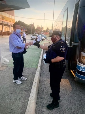 Un Policía Local de La Nucía entrega a un usuario del transporte público una mascarilla