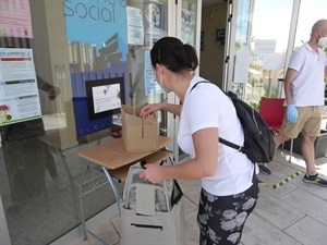 Los padres o madres de los escolares recogen los lotes de comida en el Centro Social Calvari